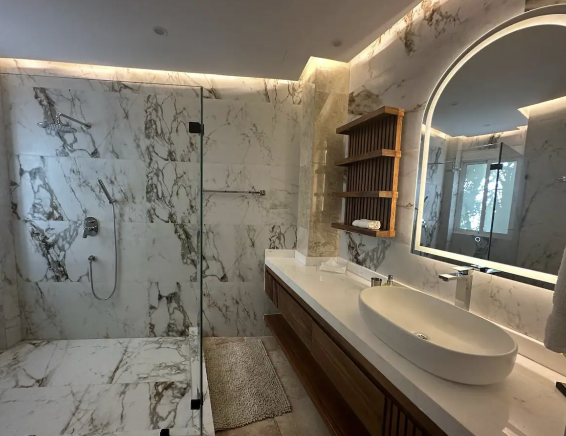 Luxe bathroom with spacious shower, marble and ample countertop at Condominios Puerta al Mar