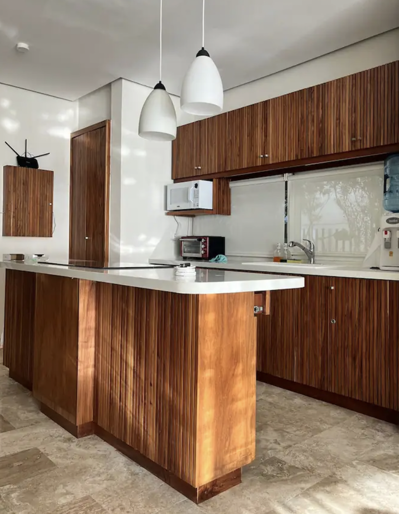 Kitchen with wood cabinets, microwave and integrated dining area in the Isla Mujeres apartment