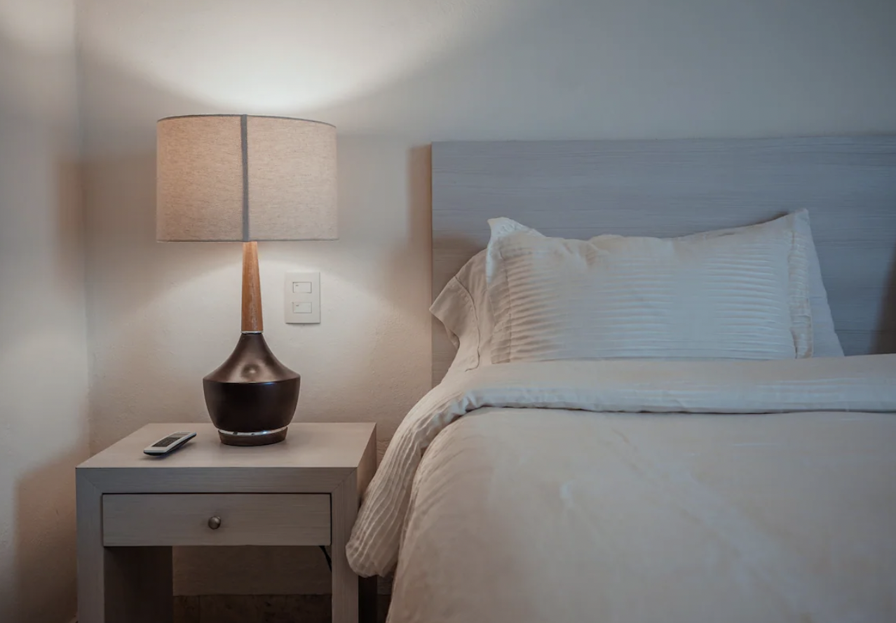 Nightstand detail with lamp and hotel-grade linens in the Isla Mujeres vacation apartment