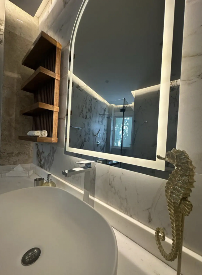 Detail of sink and backlit mirror in master bathroom of the apartment