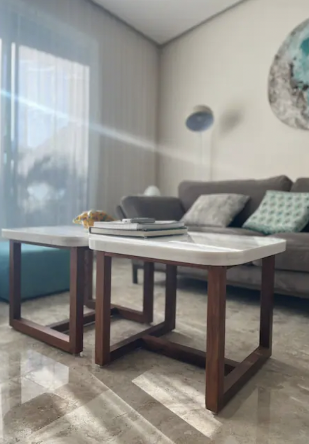 Detail of marble and wood coffee tables in living room lit by natural light