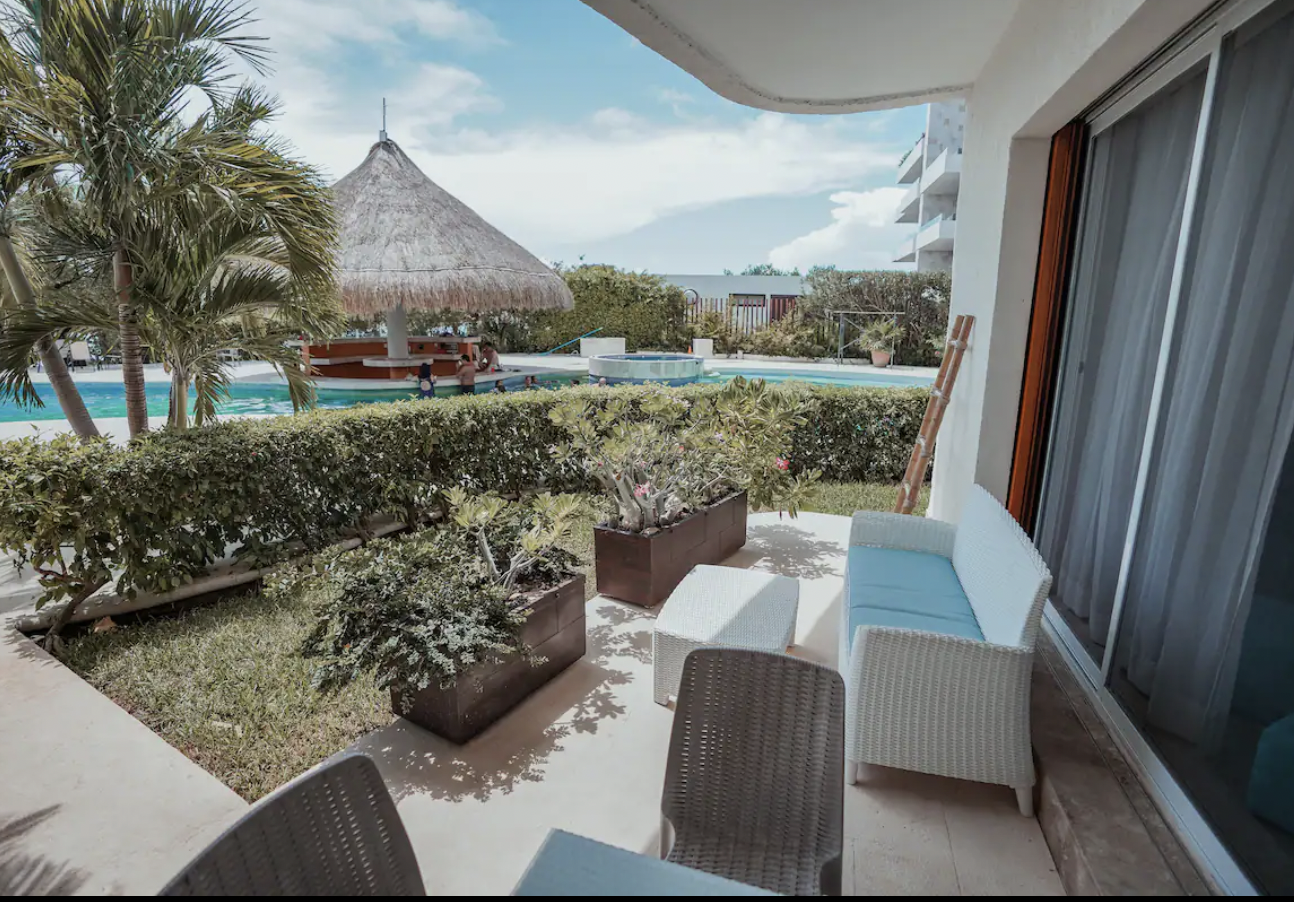 Landscaped terrace with outdoor lounge overlooking the pool and palapa of Condominios Puerta al Mar