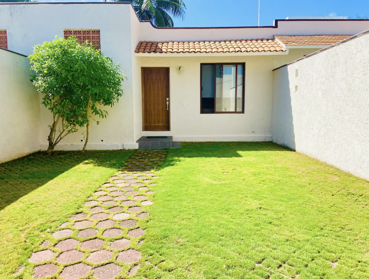 Private garden with lawn and the facade of Villa La Ceiba in Playa del Carmen