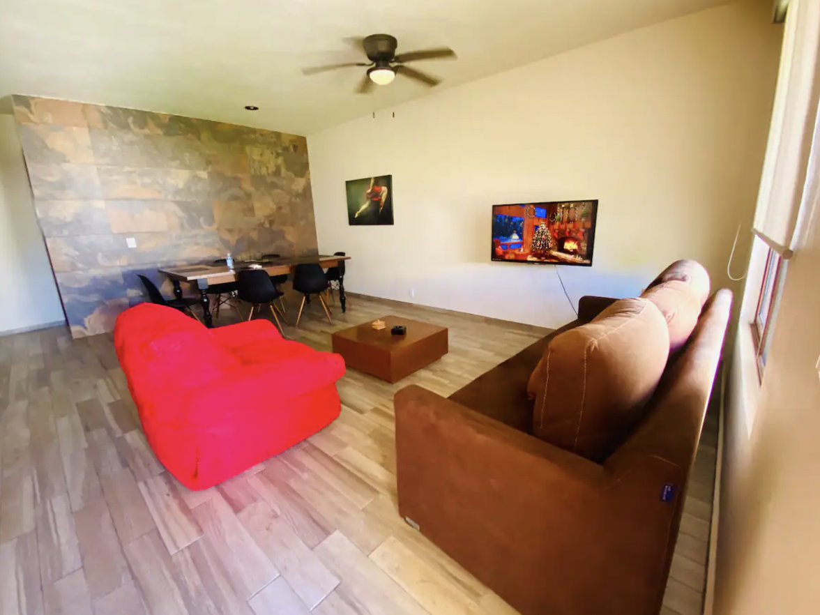 Spacious living room with brown sofa, red armchair, TV and ceiling fan at Villa La Ceiba