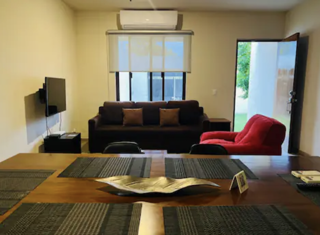 Living-dining area with brown sofa, red armchair and wooden dining table